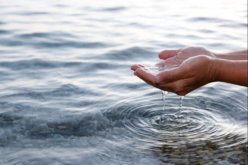 Mains recueillant de l’eau dans un environnement naturel